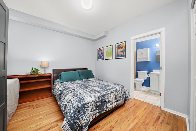 bedroom with connected bathroom and light hardwood / wood-style flooring