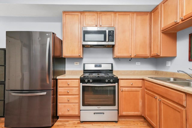 kitchen featuring sink, stainless steel appliances, light hardwood / wood-style floors, and light brown cabinets