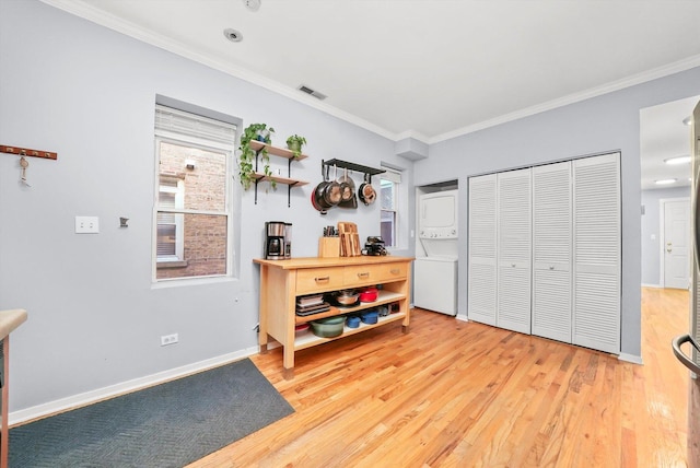 interior space featuring stacked washer / dryer, crown molding, a closet, and light hardwood / wood-style flooring