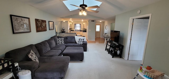 carpeted living room featuring ceiling fan and vaulted ceiling with skylight