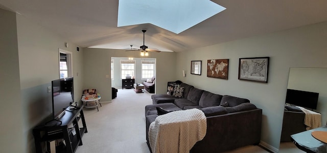 carpeted living room featuring lofted ceiling with skylight and ceiling fan