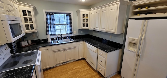 kitchen with sink, white cabinetry, light wood-type flooring, dark stone countertops, and white appliances