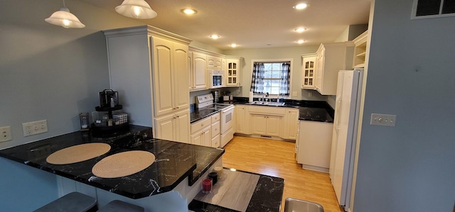 kitchen featuring sink, light hardwood / wood-style flooring, kitchen peninsula, pendant lighting, and white appliances