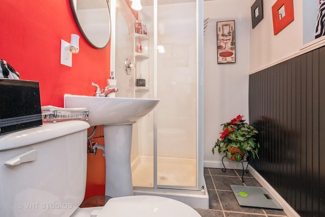 bathroom with tile patterned floors, toilet, and a shower with door