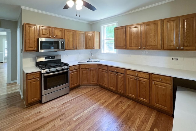 kitchen with sink, backsplash, stainless steel appliances, crown molding, and light hardwood / wood-style flooring