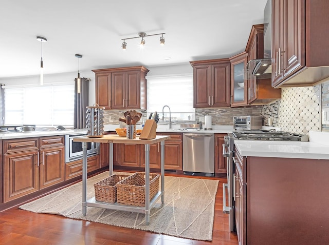 kitchen with pendant lighting, sink, backsplash, stainless steel appliances, and dark hardwood / wood-style flooring