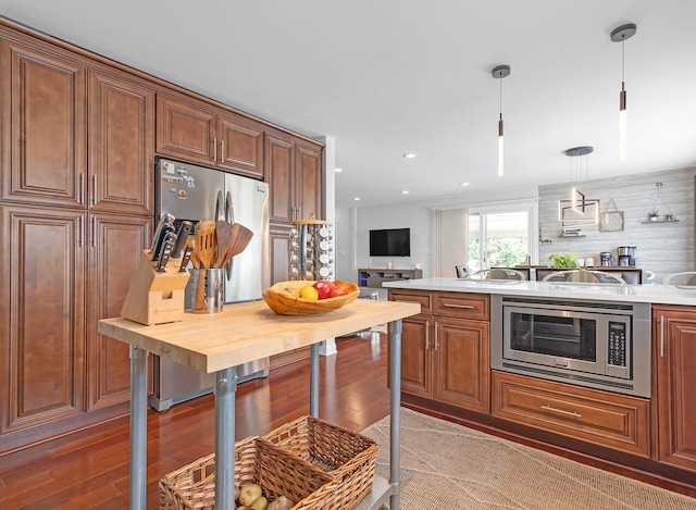 kitchen featuring wood-type flooring, pendant lighting, and stainless steel microwave