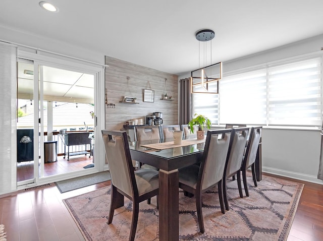 dining space with dark wood-type flooring and wooden walls