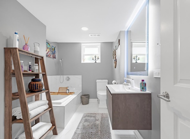 bathroom featuring vanity, tiled bath, and toilet