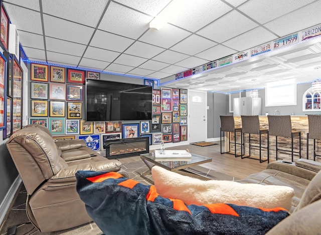 living room with a drop ceiling and wood-type flooring