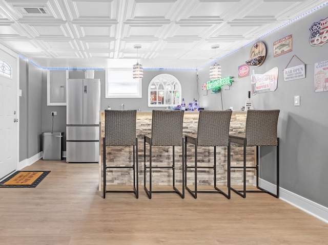 bar with stainless steel fridge and light wood-type flooring