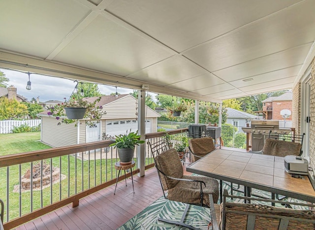 wooden terrace with area for grilling, a garage, an outbuilding, and a lawn