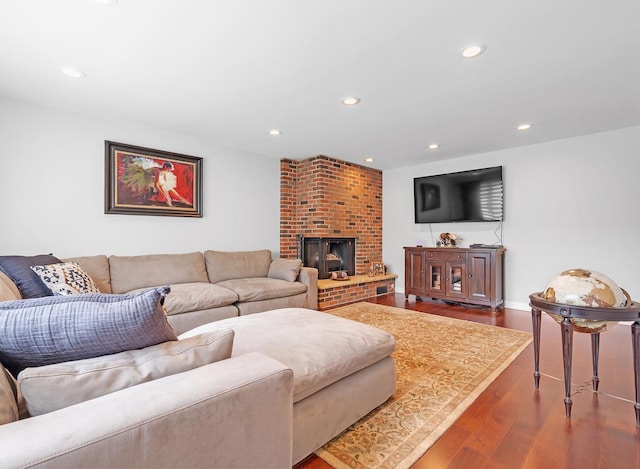 living room with a brick fireplace and hardwood / wood-style flooring