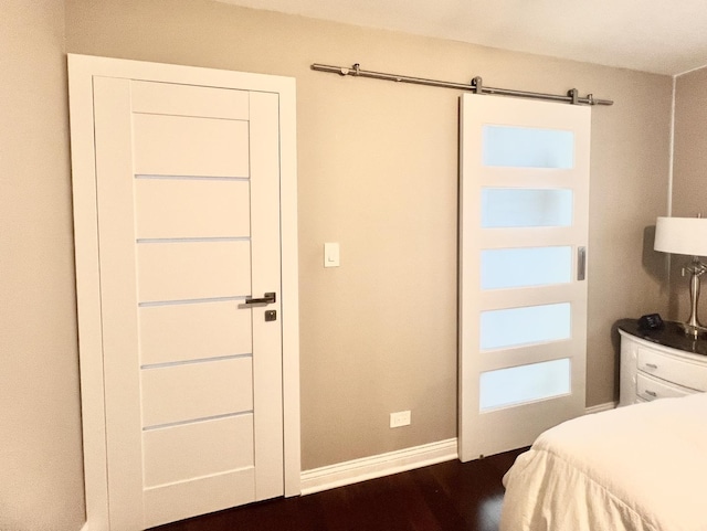 bedroom featuring a barn door and dark hardwood / wood-style flooring