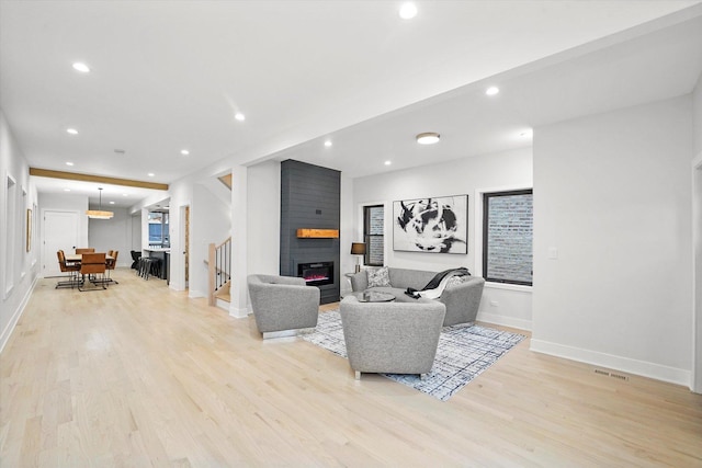 living room featuring recessed lighting, a large fireplace, stairway, and light wood finished floors