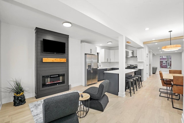 living area featuring recessed lighting, a fireplace, light wood-style flooring, and baseboards