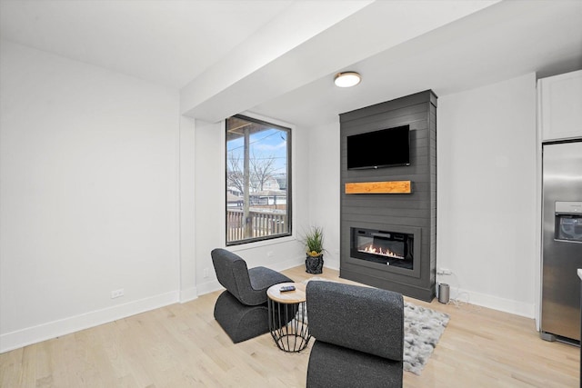 living area with light wood finished floors, a fireplace, and baseboards