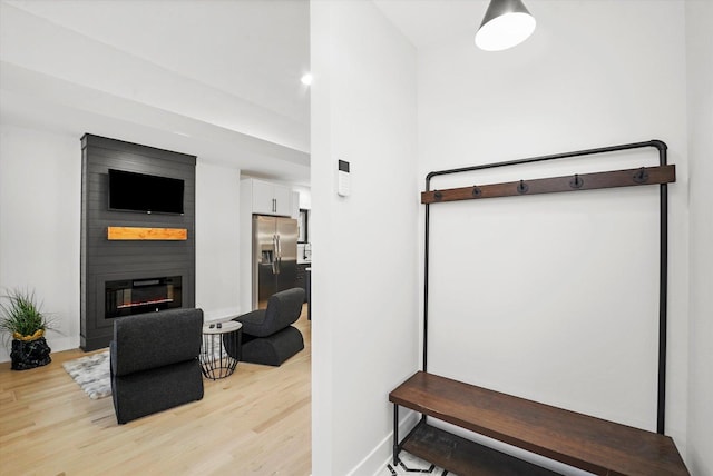 interior space with light wood-type flooring, a large fireplace, and baseboards