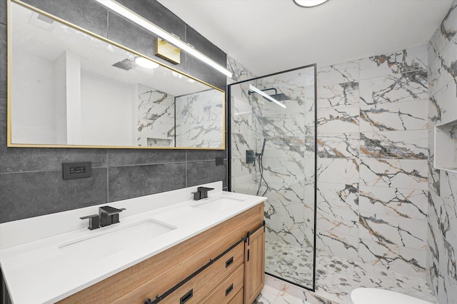 bathroom with marble finish floor, a marble finish shower, tile walls, and a sink