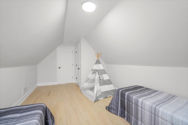 bedroom with visible vents, vaulted ceiling, baseboards, and wood finished floors