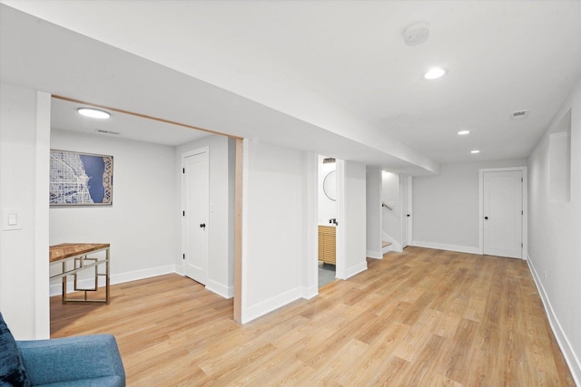 finished basement featuring recessed lighting, visible vents, stairway, light wood-style flooring, and baseboards