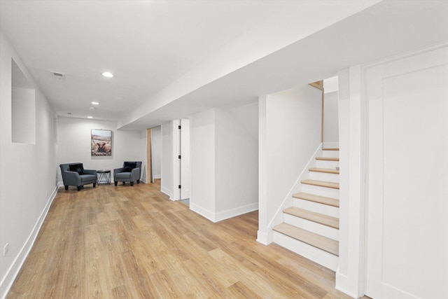 finished below grade area with light wood finished floors, recessed lighting, visible vents, baseboards, and stairs