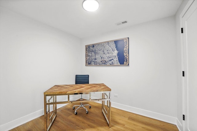 office space featuring baseboards, visible vents, and wood finished floors