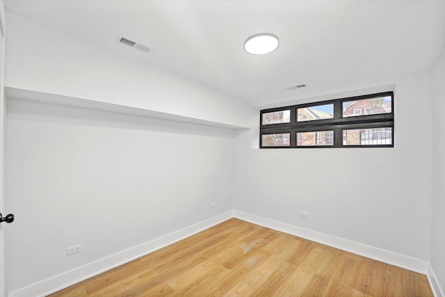 empty room with baseboards, visible vents, and wood finished floors