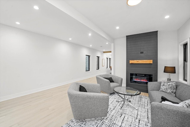 living area with a large fireplace, baseboards, light wood-style floors, and recessed lighting