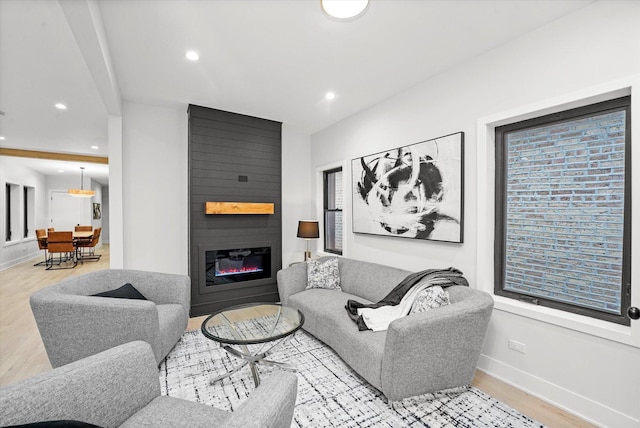 living area featuring recessed lighting, a fireplace, baseboards, and wood finished floors