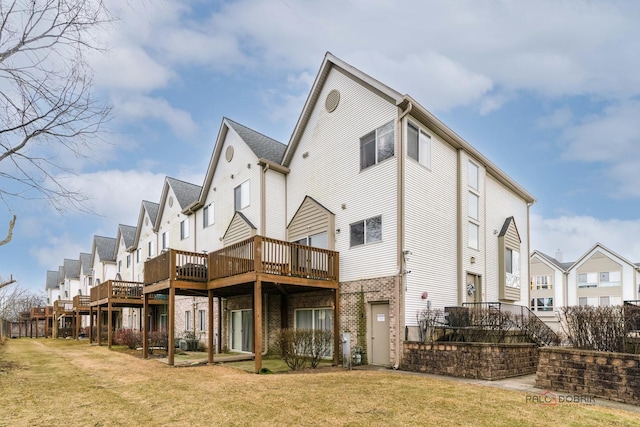 back of property featuring a wooden deck and a lawn