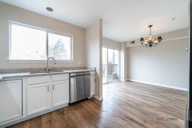 kitchen with pendant lighting, sink, white cabinets, stainless steel dishwasher, and light wood-type flooring