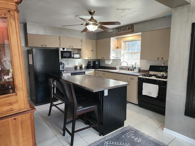 kitchen featuring sink, a center island, cream cabinets, black appliances, and a kitchen bar