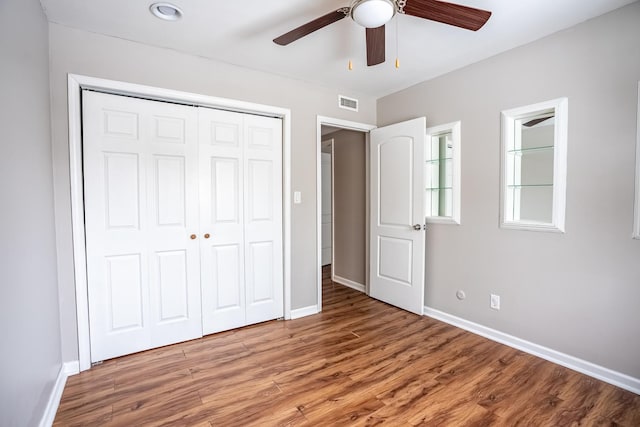 unfurnished bedroom featuring wood-type flooring, ceiling fan, and a closet