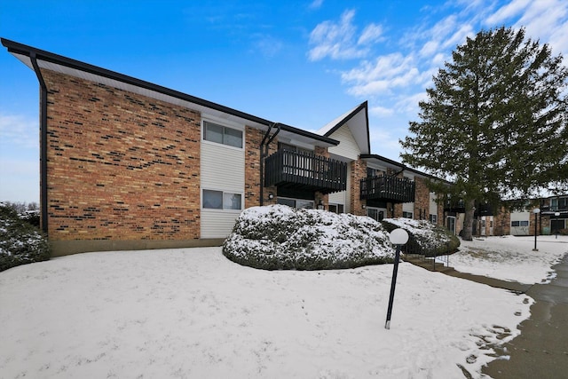 snow covered property featuring brick siding