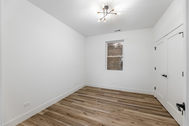 spare room featuring an inviting chandelier and hardwood / wood-style flooring