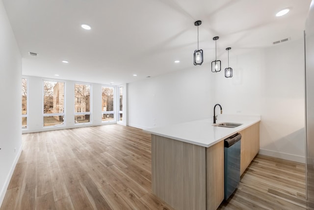 kitchen featuring sink, decorative light fixtures, kitchen peninsula, and light wood-type flooring