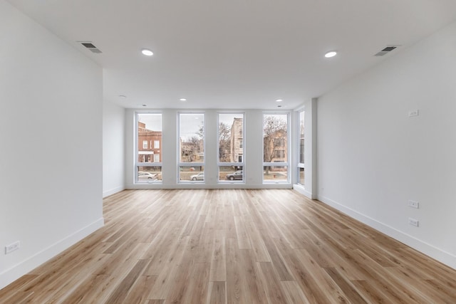 unfurnished living room with floor to ceiling windows and light hardwood / wood-style floors