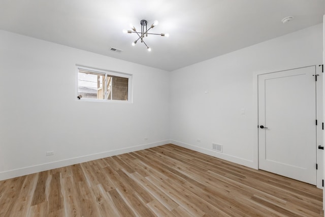 unfurnished room featuring light hardwood / wood-style flooring and a notable chandelier