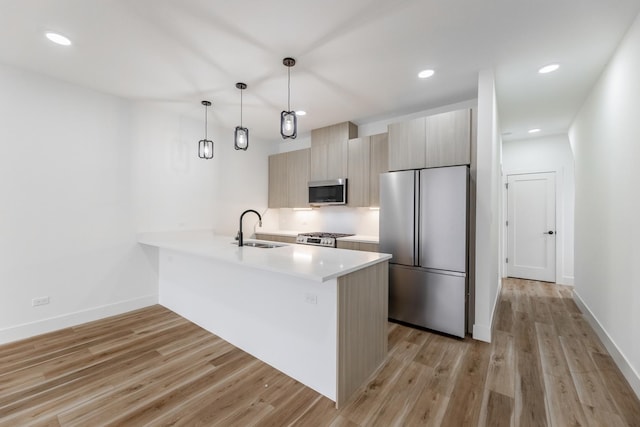 kitchen featuring sink, decorative light fixtures, light hardwood / wood-style floors, and appliances with stainless steel finishes