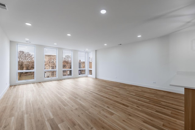 unfurnished living room featuring floor to ceiling windows and light wood-type flooring