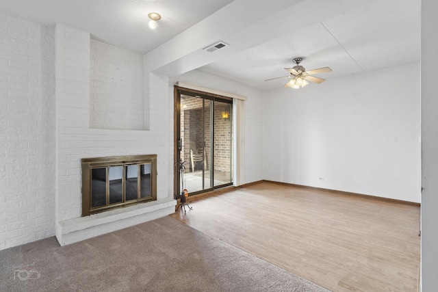 unfurnished living room with a brick fireplace, hardwood / wood-style floors, and ceiling fan