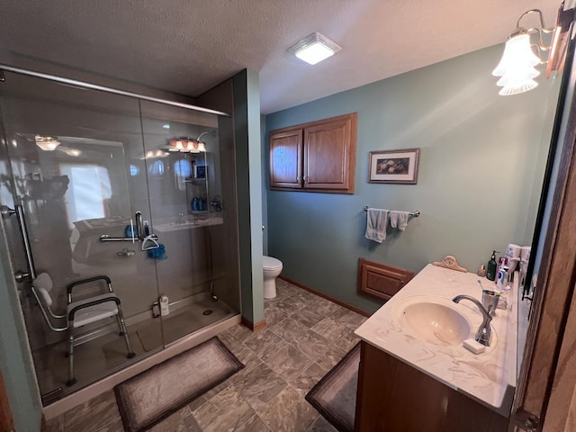 bathroom featuring vanity, a textured ceiling, a shower with shower door, and toilet