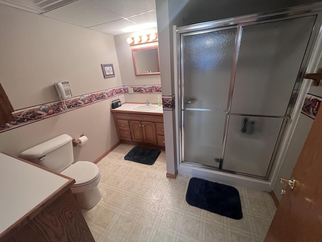 bathroom with a paneled ceiling, vanity, toilet, and a shower with shower door