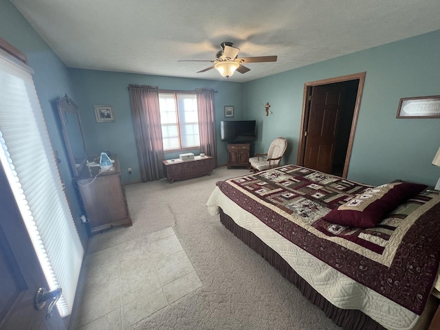 bedroom with ceiling fan, light colored carpet, and a textured ceiling