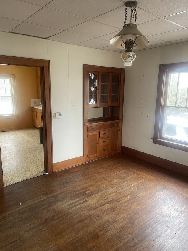 unfurnished dining area featuring a paneled ceiling and dark hardwood / wood-style floors