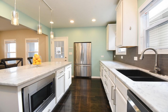 kitchen featuring sink, appliances with stainless steel finishes, hanging light fixtures, a center island, and white cabinets