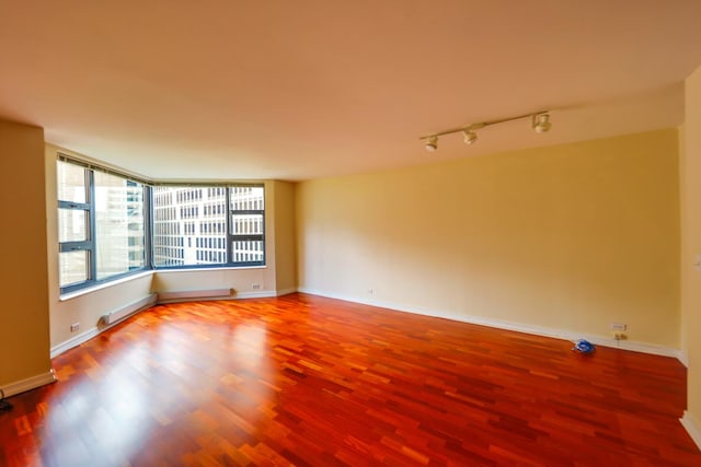 unfurnished room featuring hardwood / wood-style flooring and track lighting