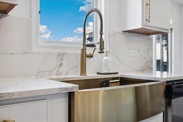 kitchen featuring white cabinetry, dishwasher, backsplash, and light stone countertops