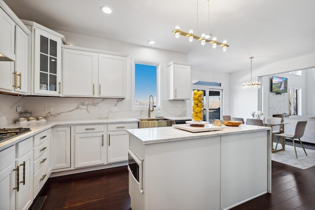 kitchen featuring white cabinets, a kitchen island, dark wood-style flooring, a chandelier, and a sink